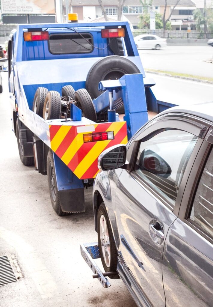 tow truck towing a broken down car on the street 1 e1632119620136